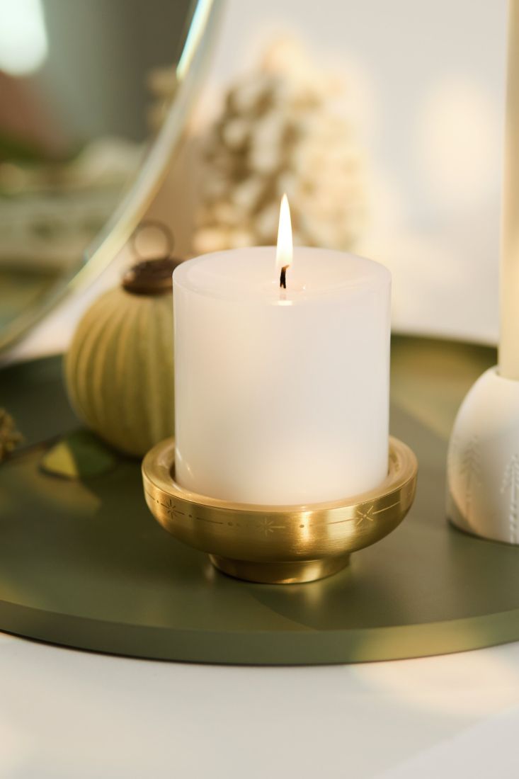 Der goldene räder Messing Kerzenhalter mit brennender Stumpenkerze als festliche Tischdekoration in der Adventszeit