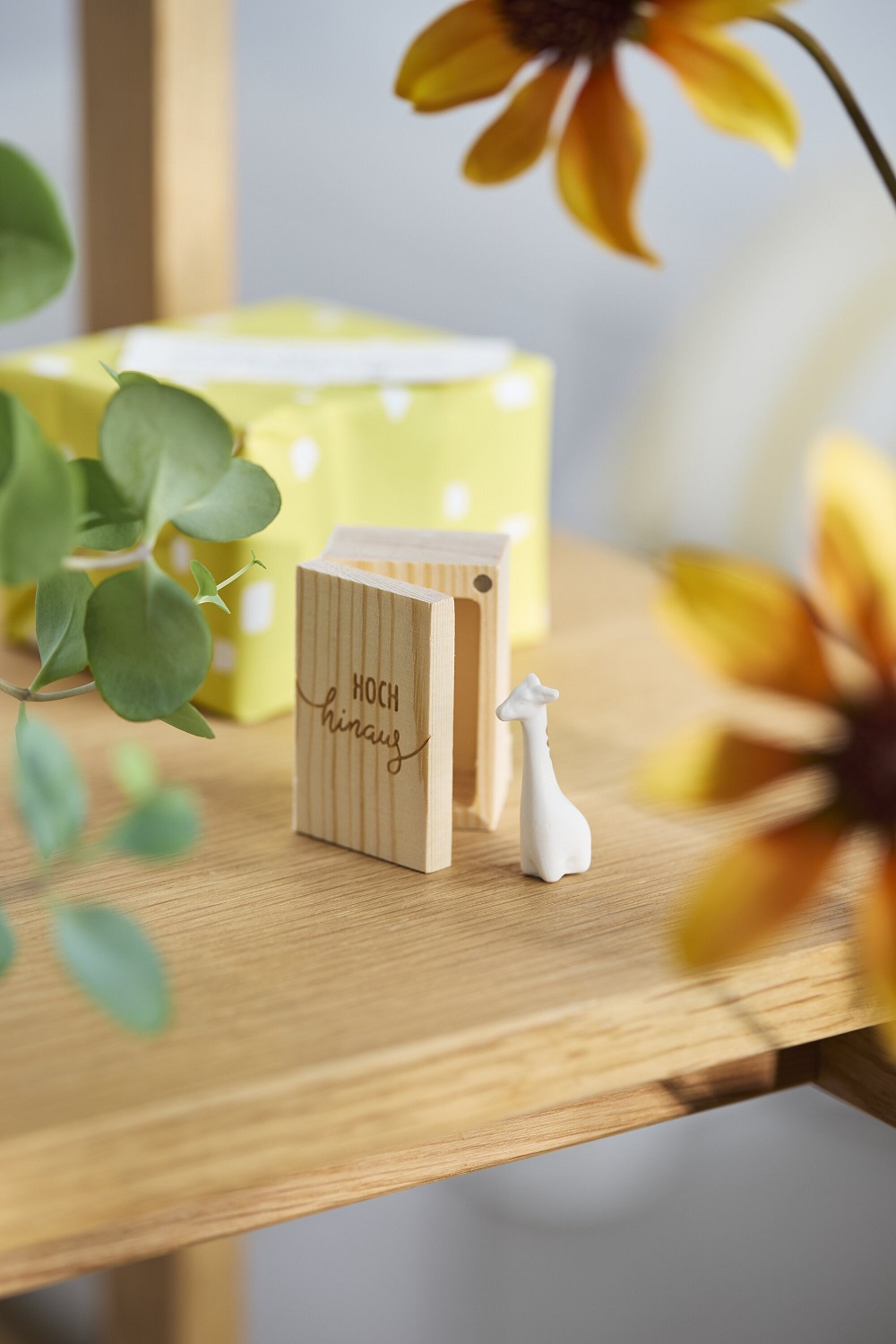 holzbuch, Miniaturenszene, weißeGiraffe, gelbesGeschenkbox, GrünesPflanzenblatt