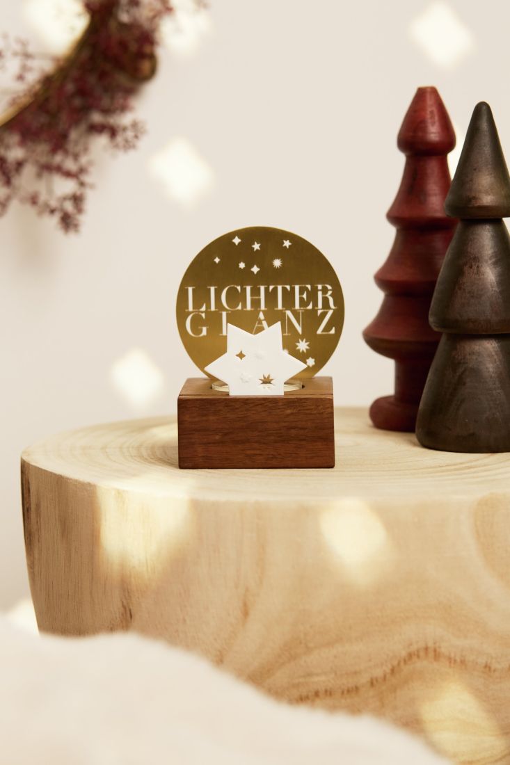 Das räder Lichtobjekt Lichterglanz stimmungsvoll beleuchtet mit einem Teelicht, dessen Schein durch die Stanzungen des Schriftzugs und des Porzellansterns schimmert