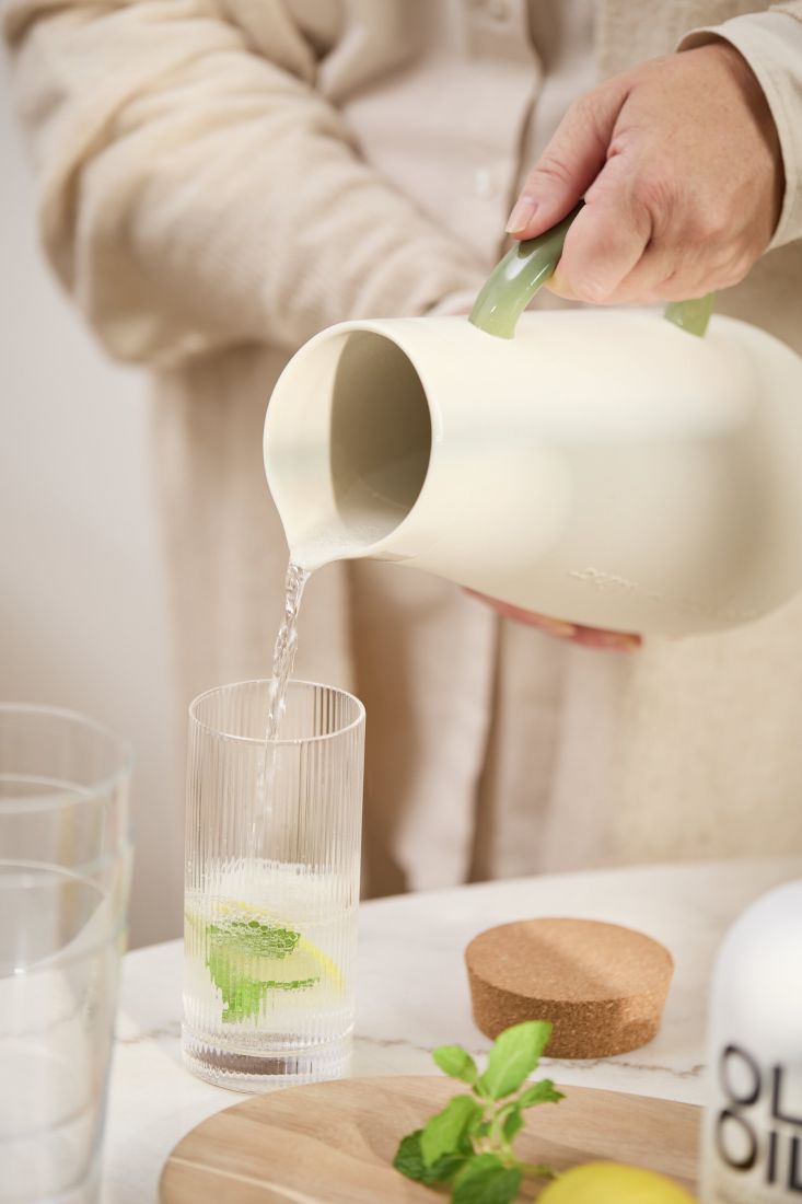 Gefüllter räder Krug Aqua e vino auf einem gedeckten Tisch mit Gläsern