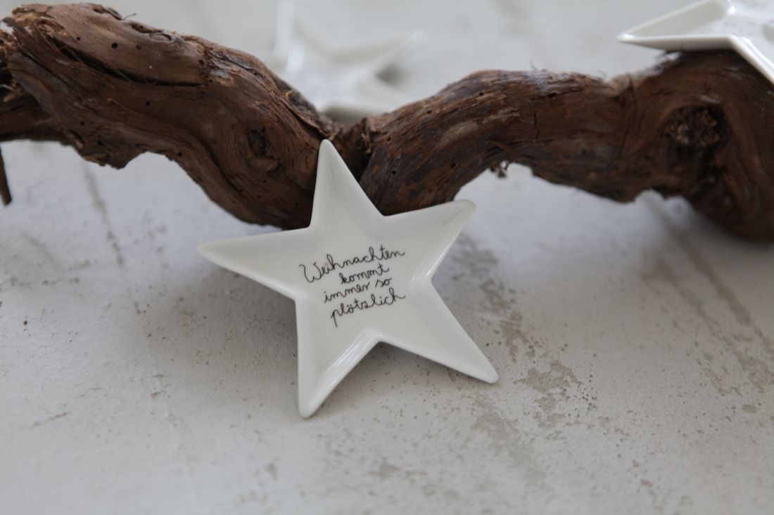 Kleiner Porzellan-Sternteller mit lustigem Weihnachtsspruch dekoriert auf einem Tisch