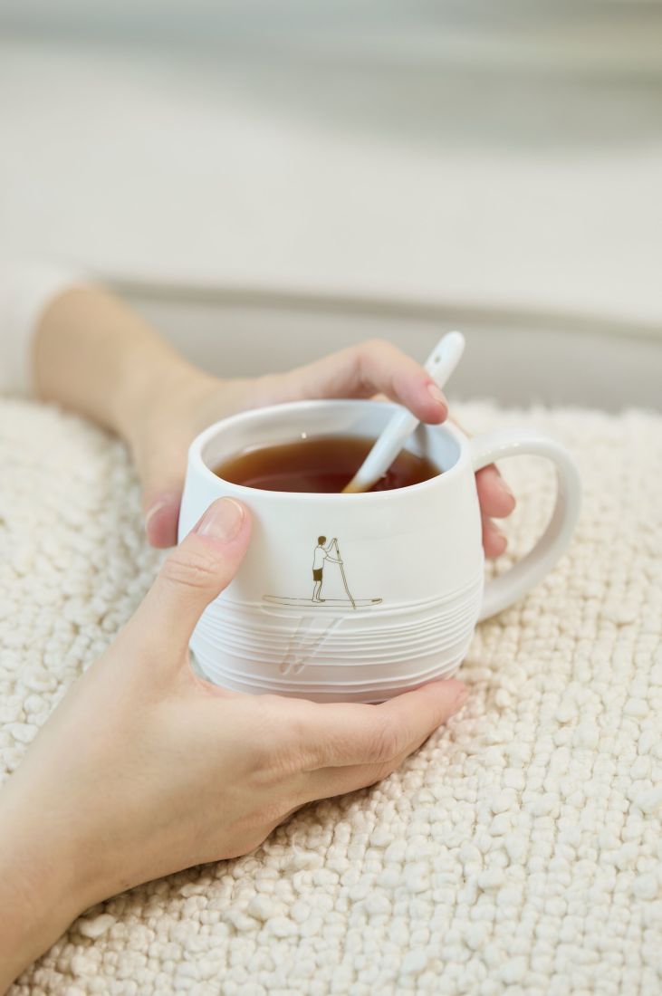 Die Tasse Lass dich treiben in den Händen auf einer Decke