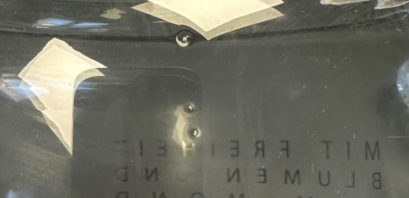 glossy surface, sticker residue, dark panel, rectangular plate, mirrored text