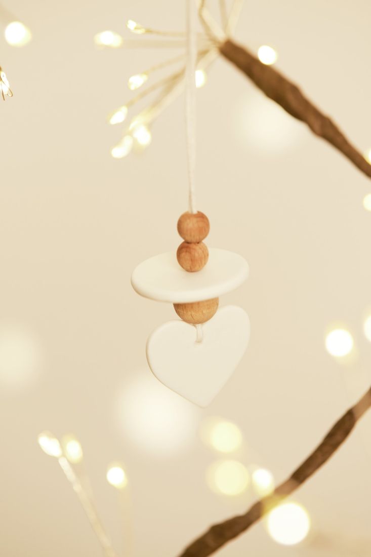 Filigraner räder Porzellan-Anhänger Herz als edler Schmuck an einem winterlichen Zweig