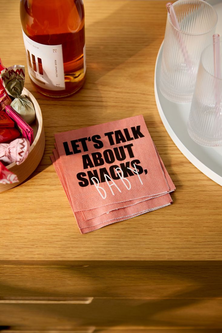 Nahaufnahme der kleinen räder Serviette Let´s talk about Snacks Baby stilvoll dekoriert neben einer Schale mit Knabbereien