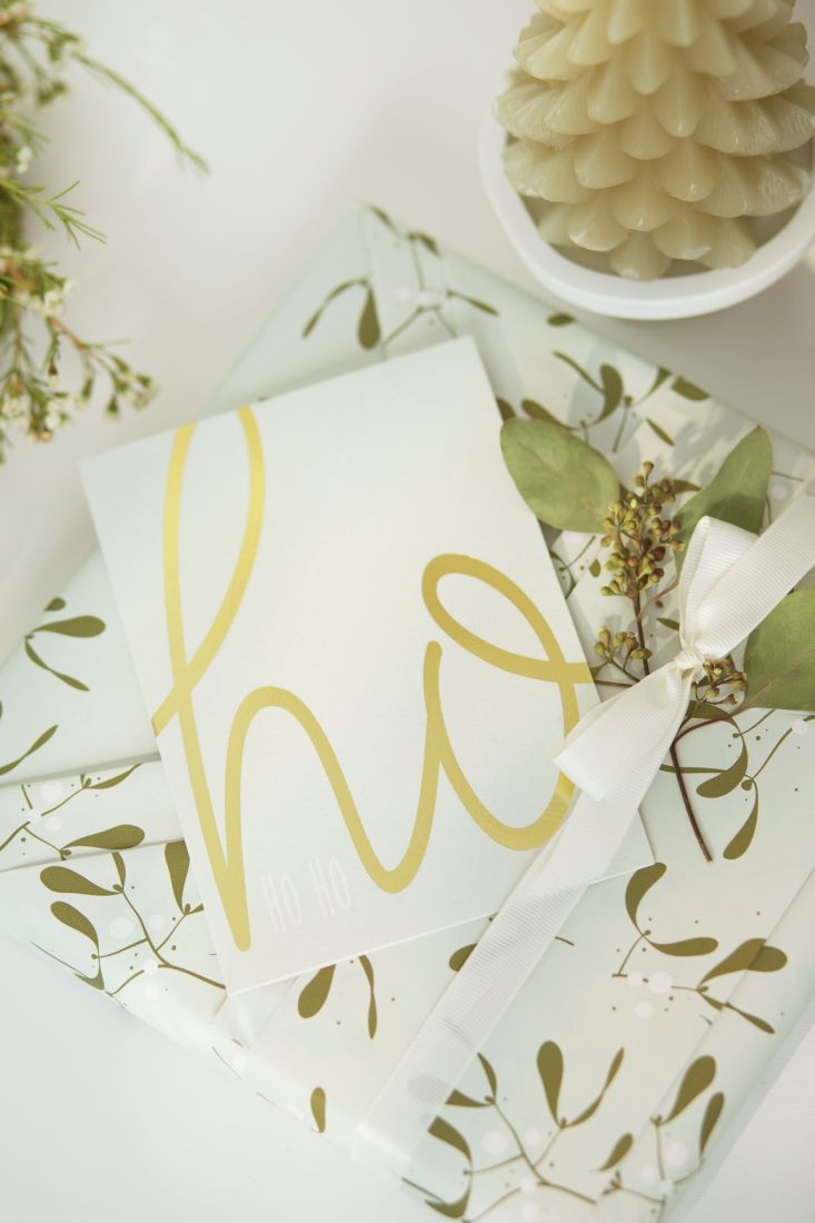 Die räder Schriftkarte Ho Ho Ho stilvoll als Beilage zu einem verpackten Weihnachtsgeschenk arrangiert