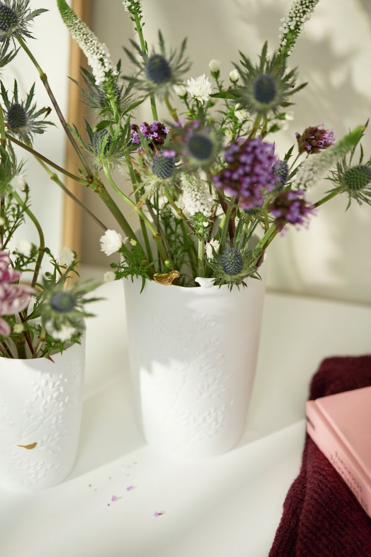 Dekorierte räder Vase Vogelpaar mit frischen Frühlingsblumen auf einem hellen Holztisch
