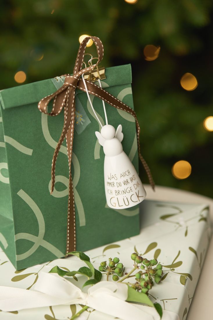 Der kleine räder Schutzengel aus Porzellan dekorativ an einem Geschenk aufgehängt als liebevoller Glücksbringer