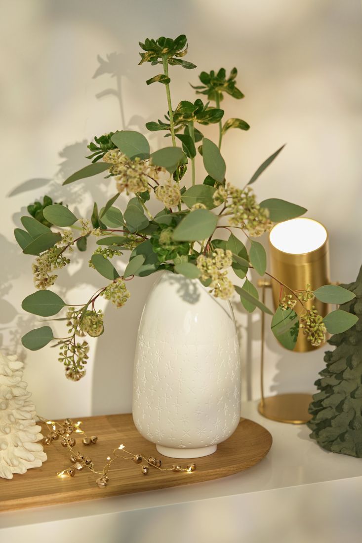 Die räder Porzellanvase Sterne dekorativ mit Eukalyptus arrangiert auf einem festlichen Tisch