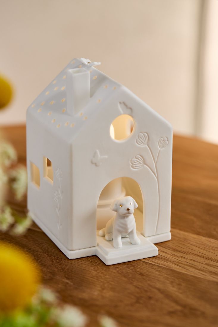 Warm leuchtendes räder Porzellan-Lichthaus Hund mit gemütlichem Kerzenschein auf dem Wohnzimmertisch
