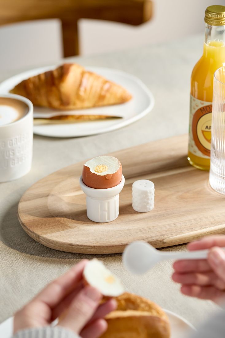 Das dekorative räder Eierbecher Set Good start stilvoll arrangiert auf einem hölzernen Frühstückstisch