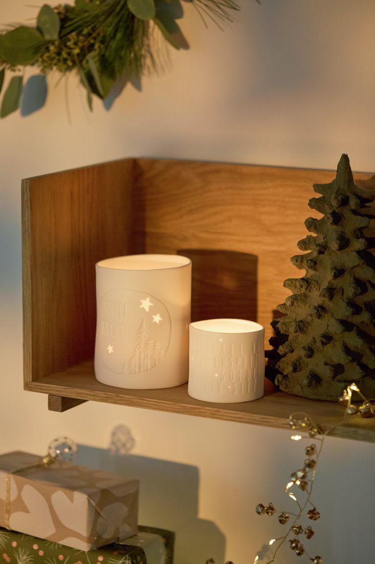 Stimmungsvoll leuchtendes räder Porzellan-Teelicht mit weihnachtlicher Botschaft in einer gemütlichen Adventsdekoration