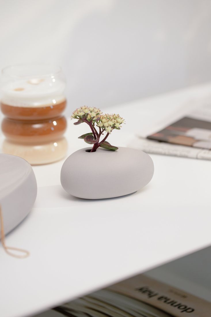 Moderne Dekoration mit der räder Vase Kiesel und einem einzelnen Zweig auf einem Sideboard