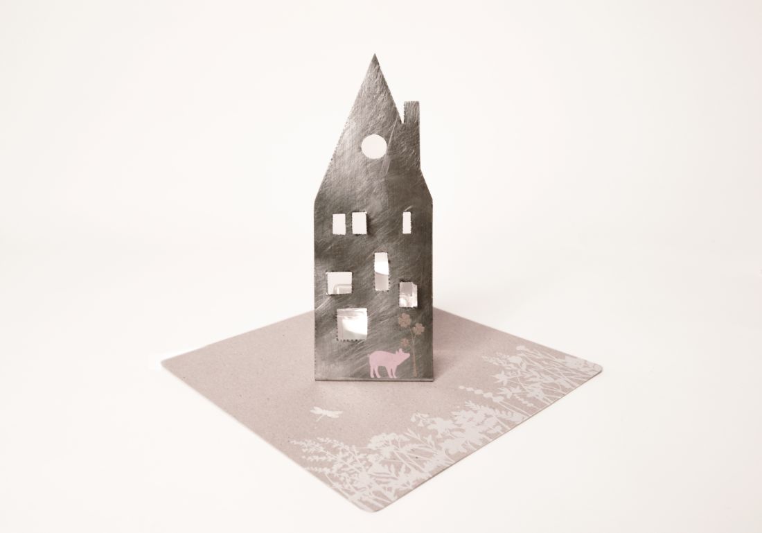 Große Karte Zuhause Lichter Glücksschwein von Good old friends mit aufgestelltem Metallhaus, rosa Glücksschwein-Print und weißem Wiesenblumenmuster