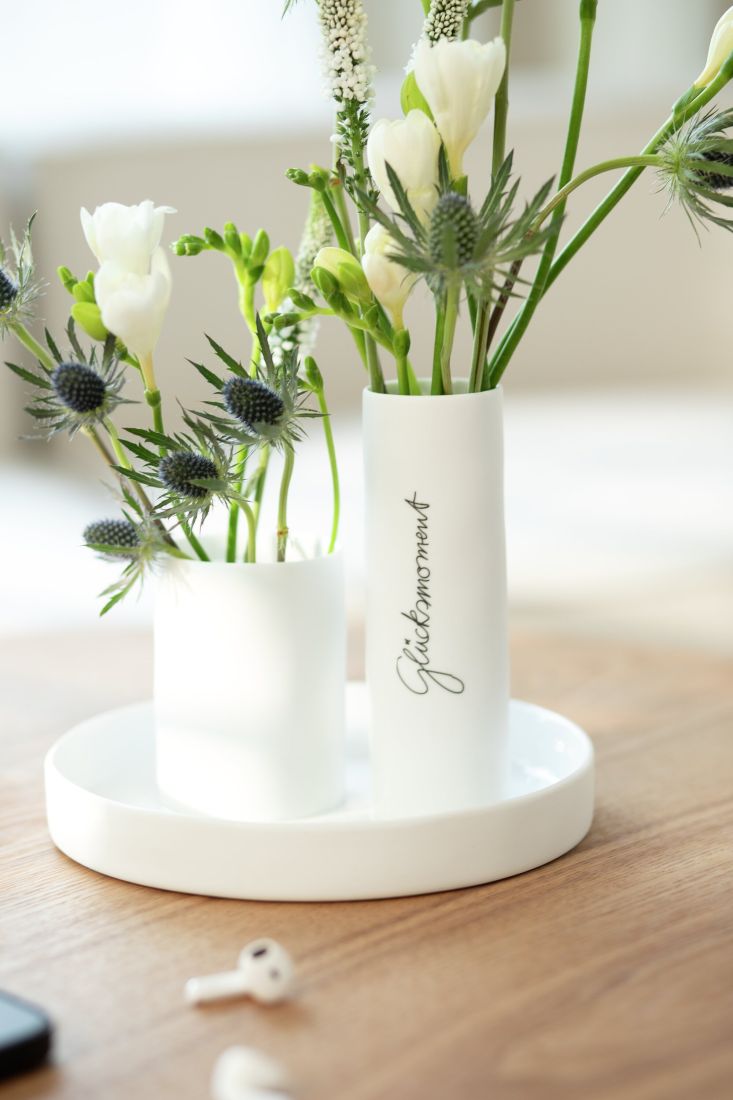 Dekorierte räder Vase Mittelpunkt mit zwei einzelnen Frühlingsblumen auf einem gedeckten Tisch