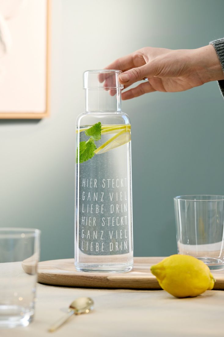 Die räder Glaskaraffe gefüllt mit frischem Wasser und Minze auf einem sommerlich gedeckten Gartentisch