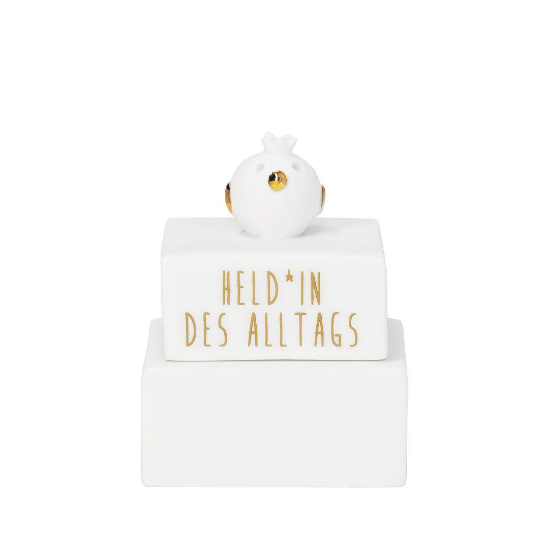 Weiße räder Porzellan-Trophäe mit einer kleinen goldenen Vogelfigur auf dem Deckel und dem goldenen Schriftzug Held*in des Alltags
