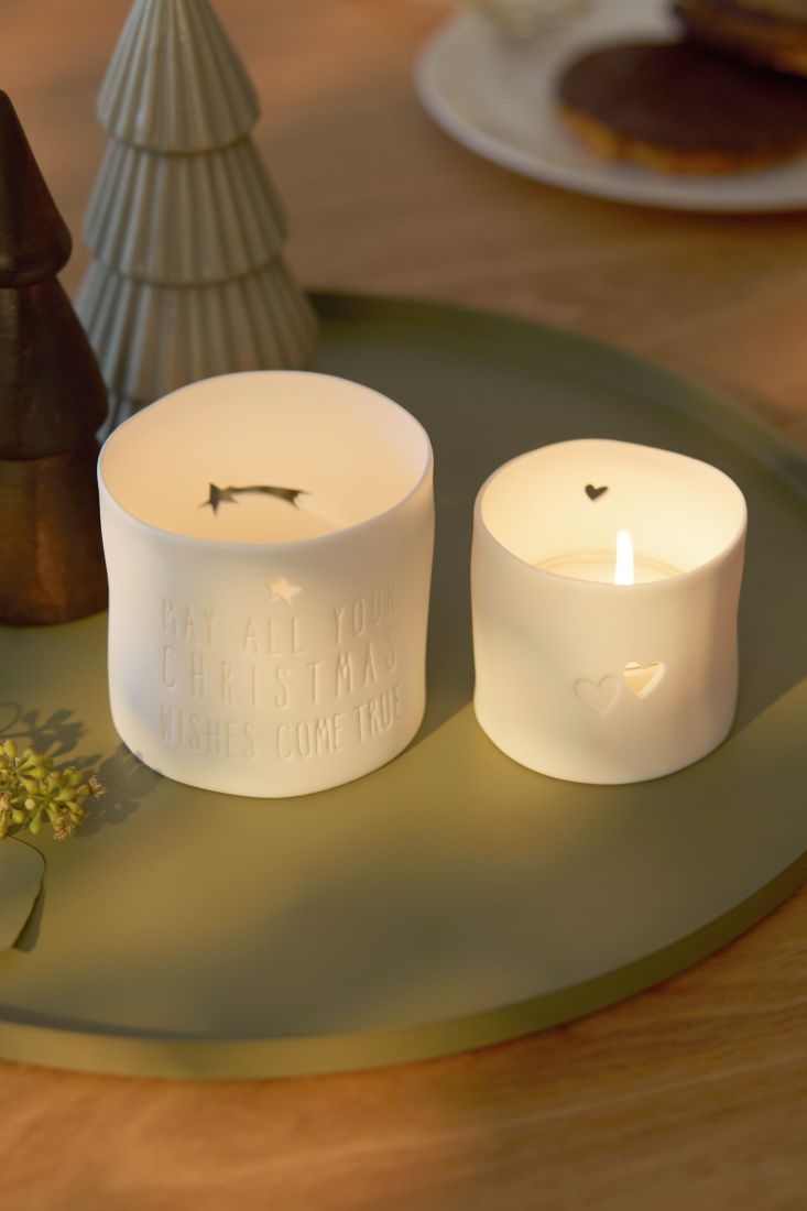 Stimmungsvoll leuchtendes räder Porzellan-Teelicht mit Stern-Lichtschein in einer winterlichen Dekoration
