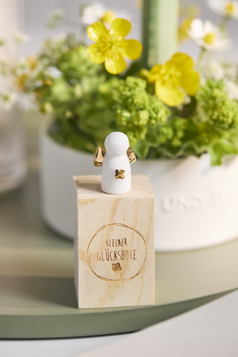 kleiner glücksbote, engelfigur, holzblock, weiße figur, goldene details
