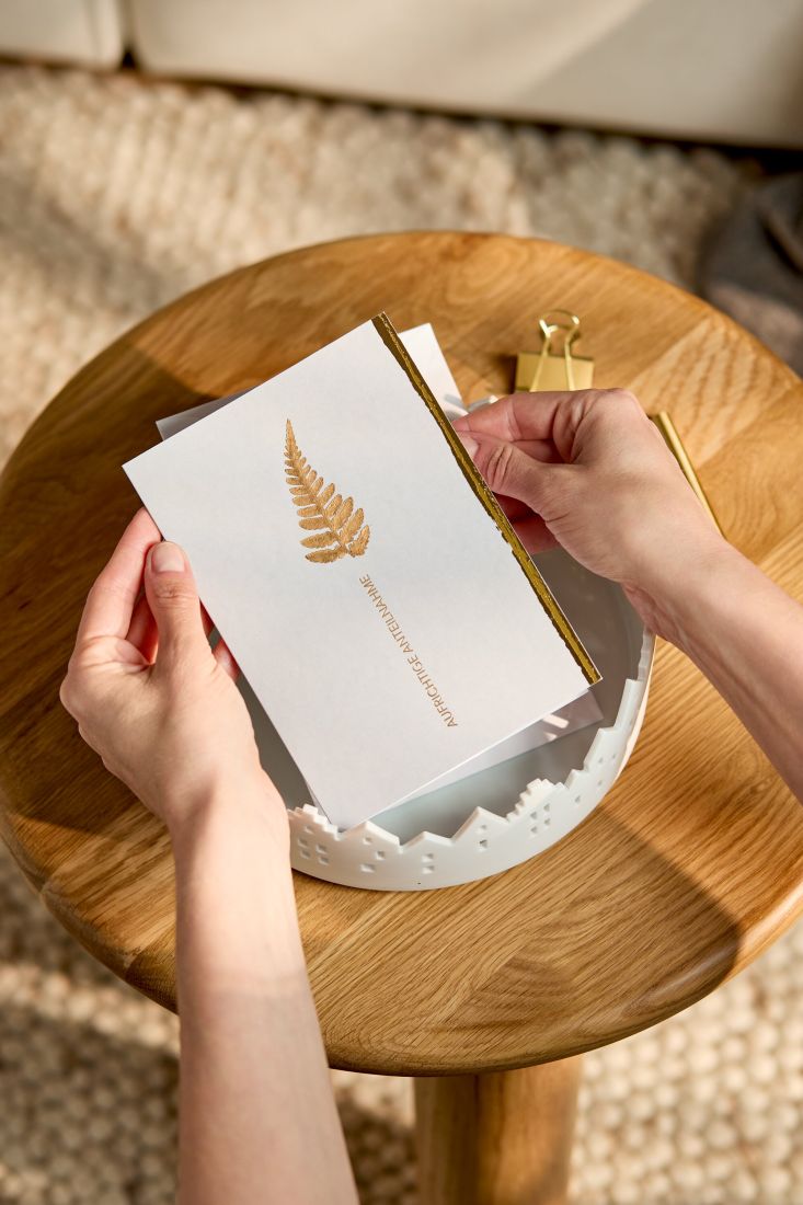 Nahaufnahme der grauen räder Beileidskarte mit Fokus auf das filigrane echte Blatt und die goldene Prägung