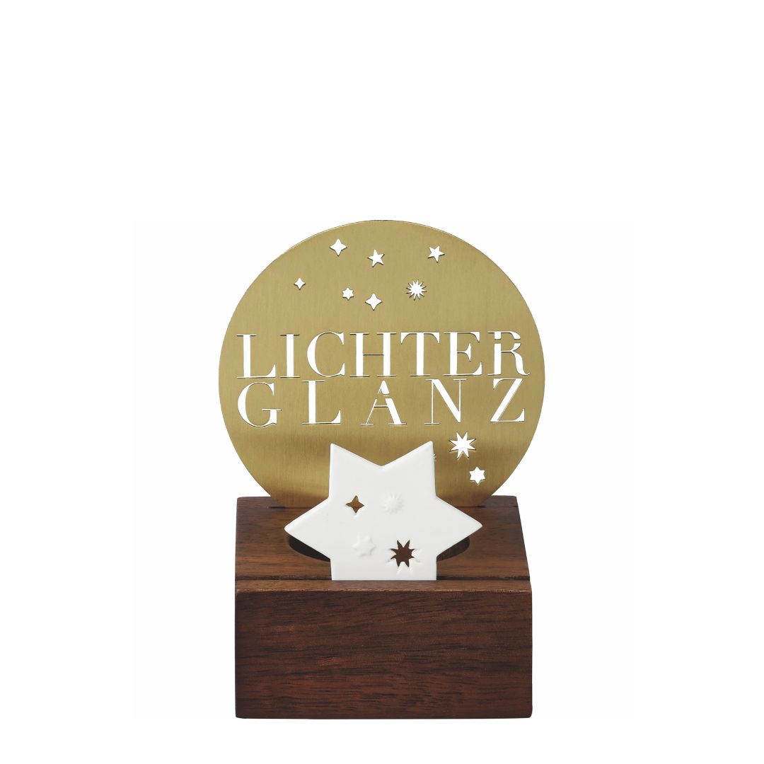 Lichtobjekt Lichterglanz von räder mit dunklem Eschenholz-Sockel, goldfarbener runder Metall-Rückwand mit ausgestanztem Schriftzug LICHTERGLANZ und weißem Porzellanstern