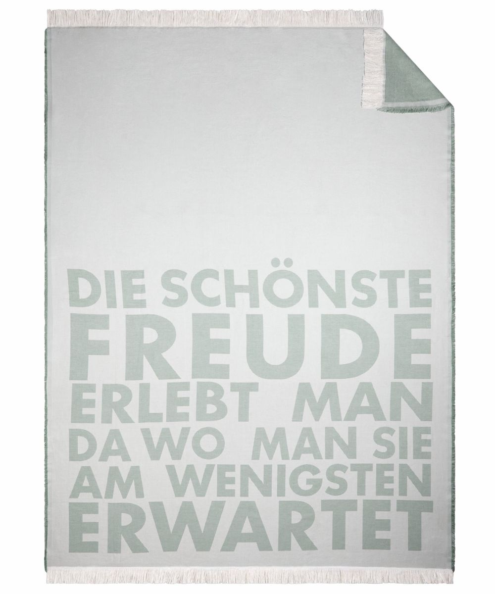 Große räder Kuscheldecke Freude in Türkis und Weiß aus 100% Baumwolle auf einem Sofa