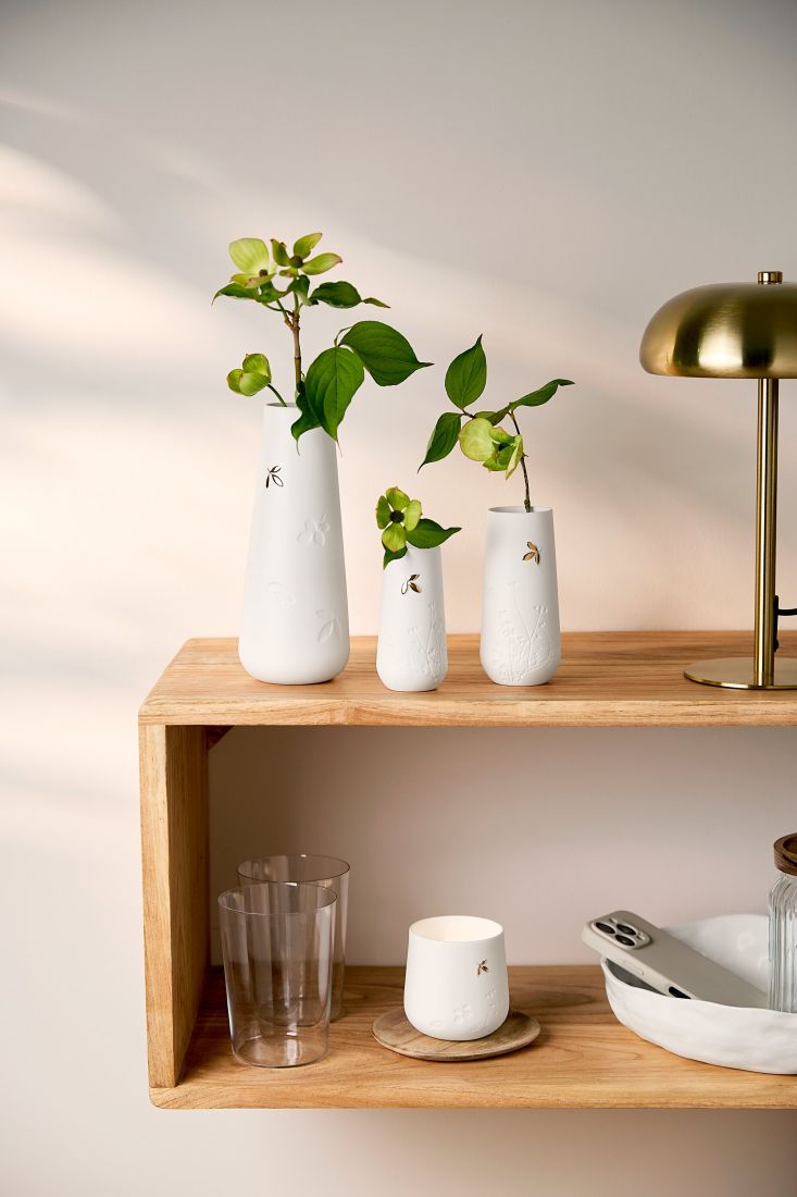 Die elegante räder Goldblatt Vase dekoriert mit einer zarten Blüte auf einem hellen Holztisch
